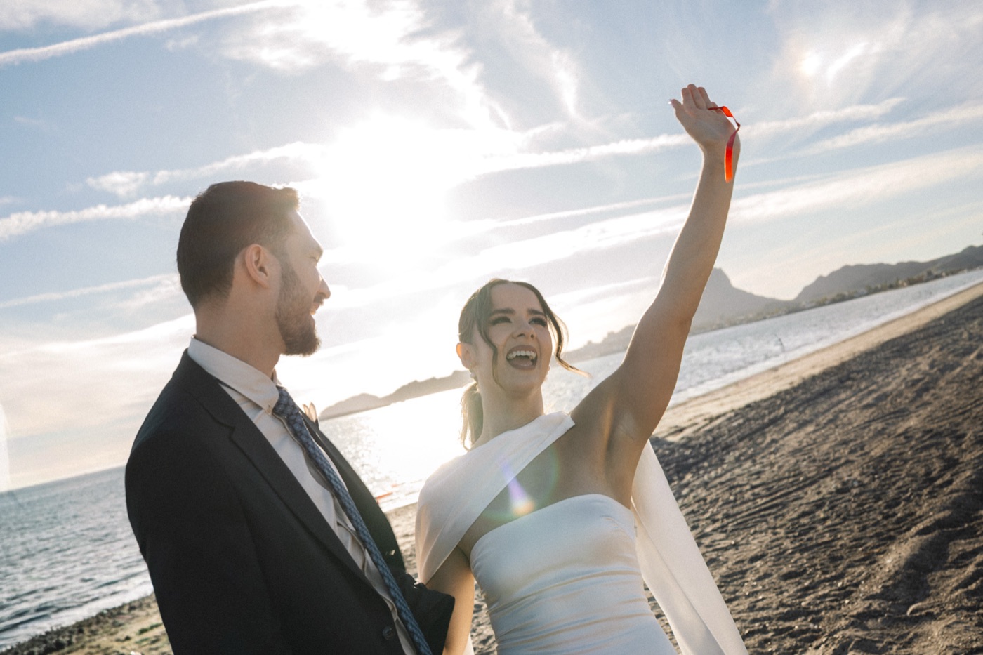 Los novios con los brazos en alto frente al mar